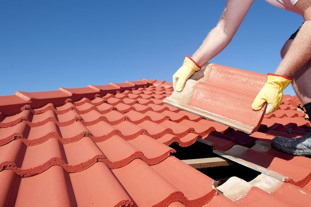 A roofer repairing titles on a roof